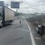 Imagem do trecho da rodovia onde ocorreu o acidente, com a motocicleta apoiada na barreira de concreto da via e o caminhão na faixa da direita