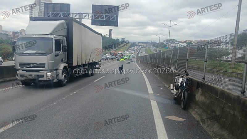 Imagem do trecho da rodovia onde ocorreu o acidente, com a motocicleta apoiada na barreira de concreto da via e o caminhão na faixa da direita