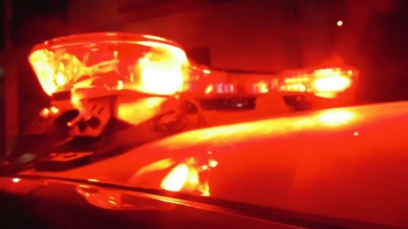 A imagem mostra as luzes de emergência (giroflex) acesas no teto de uma viatura policial durante a noite.