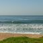 Praia Vermelha do Norte com faixa de areia, mar com ondas fortes e vegetação às margens da praia