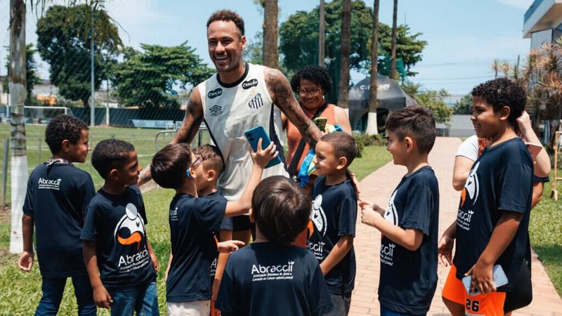 Imagem de diversas crianças indo abraçar o atleta Neymar