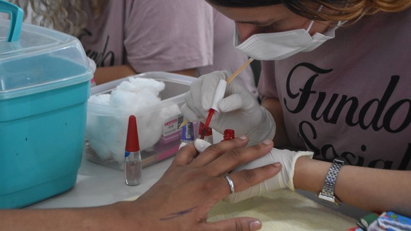Profissional da beleza pintando as unhas de uma mulher