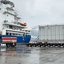 Imagem mostra operação portuária com um caminhão da Transportes Pesados Blumenau rebocando uma carreta modular com um grande transformador elétrico ao lado de um navio de carga.