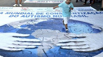 Dia Mundial de Conscientização do Autismo é celebrado em 2 de abril Governo lança cartilha para crianças com autismo Menino brincando em grande banner sobre Dia Mundial de Conscientização do Autismo - © Tania Rego/Agencia Brasil