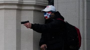 Homem usando máscara protetora aponta suas armas durante tiroteio fora da Catedral de St. John Divine em Manhatan, Nova York. - Jeenah Moon / Reuters
