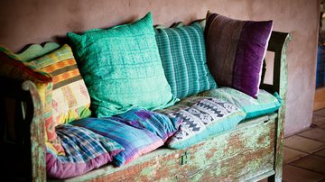 Imagem Ilustrativa  Para cego ver: um sofá de madeira com almofadas coloridas em cima, a foto é Ilustrativa - Imagem de Claire Lumley por Pixabay