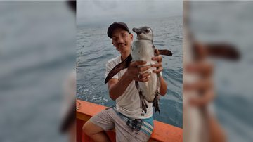 Pescador tira foto com pinguim na embarcação - Foto: Divulgação