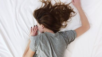 Saiba qual a melhor e qual a pior posição para dormir Mulher deitada de barriga para baixo na cama - Pixabay