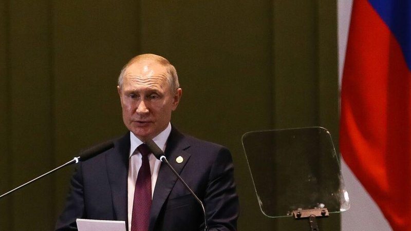 Vladimir Putin é o atual presidente da Rússia e anunciou a medida nesta quarta-feira (19) Vladimir Putin Idoso em frente a dois microfones e uma bandeira atrás - © Valter Campanato/Agência Brasil