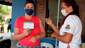 Cobertura em primeira dose na cidade é de 98,27% Ubatuba imuniza mais 67% da população contra covid Mulher segurando carteira e vacinação da covid-19 e tomando a segunda dose da vacina - Divulgação/Prefeitura de Ubatuba