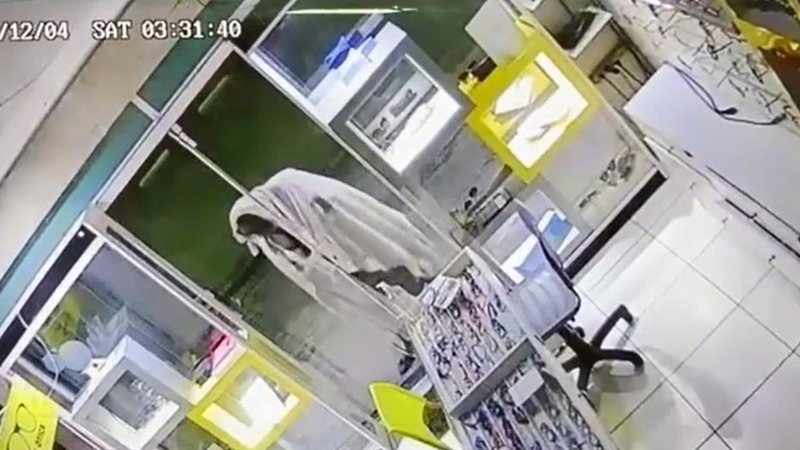 Com manta e visual fantasmagórico, homem virou 'chacota' nas redes sociais Ladrão 'fantasma' tenta invadir ótica durante a madrugada em Bertioga | VÍDEO Ladrão tentando arrombar porta de vidro de comércio no centro de Bertioga - Divulgação/Aconteceu em Bertioga