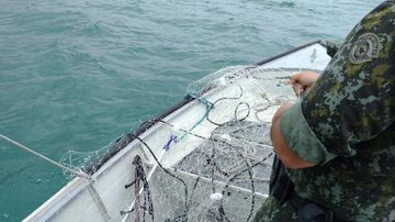 Algumas redes, como as de emalhe de fundo e de superfície, são armadas em berçários naturais de espécies marinhas Polícia Marítima de SP localiza rede de pesca irregular em Caraguatatuba após denúncia Policial dentro do barco retirando a rede do mar - Divulgação/Polícia Marítima de SP