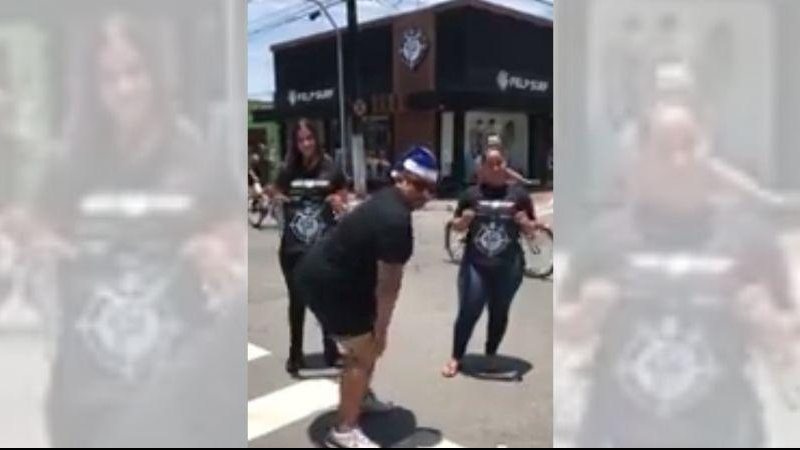 Com trilha sonora natalina dono de loja chama atenção dançando em frente ao estabelecimento Empresário aparece rebolando em vídeo gravado em Praia Grande Homem dançando na rua com touca de natal azul e duas mulheres ao fundo segurando objeto com a logomarc - Reprodução/FaceBook