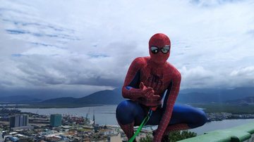 Super-herói promete emocionar o público com descida de prédio do Cine Roxy Pré-estreia do novo Homem-Aranha: super-herói descerá prédio de 11 andares em Santos Homem-aranha posando para foto com cidade ao fundo - Divulgação/Brasil Adventures