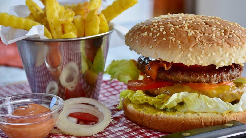 Entregador teve que arcar com o prejuízo de R$ 56,94 pois confiou na boa-fé do cliente Entregador de comida leva rolê de cliente e acaba ficando no prejú em PG Lanche com hamburguer e batatas fritas, em cima de uma toalha xadrez de vermelho e branco - Pixabay