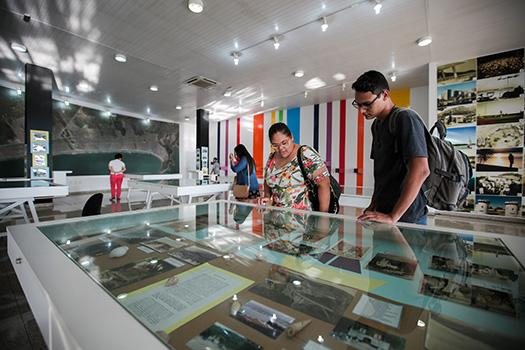 Visitação poderá ser feita até o final de março, terça a sábado Praia Grande celebra 55 anos com nova exposição no Museu da Cidade, a partir desta terça-feira (18) Pessoas vendo a exposição dentro do museu - Divulgação