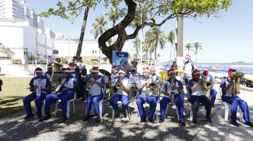 evento aconteceu na tarde última sexta-feira (10), na Praça das Bandeiras, na Praia de Pitangueiras Apresentações culturais animaram  a 12ª Virada Inclusiva em Guarujá Grupo de homens sentados em fileira tocando saxofone com o mar ao fundo - Prefeitura de Guarujá