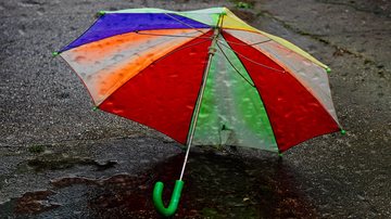 Verão 2022 está mais para "chuverão" Previsão do tempo indica que semana ainda começa com chuva no litoral de SP Guarda-chuva colorido aberto caído no asfalto molhado - Pixabay