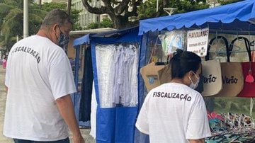Mais de 170 pessoas trabalham para manter a segurança e a ordem na cidade Guarujá reforça esquema de segurança durante a temporada Dois fiscais analisando uma feira de artesanto - Divulgação