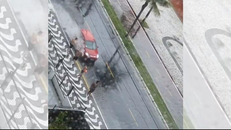 Flagrante aconteceu nesta sexta-feira (31) na orla do bairro Canto do Forte Viralizou: Vídeo flagra pessoas tomando banho de enxurrada em Praia Grande Rapazes na calçada da orla do bairro Canto do Forte em Praia Grande esperam carros passarem na enxurrada - Reprodução/Instagram