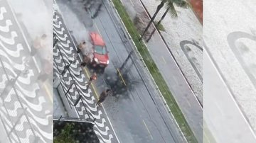 Flagrante aconteceu nesta sexta-feira (31) na orla do bairro Canto do Forte Viralizou: Vídeo flagra pessoas tomando banho de enxurrada em Praia Grande Rapazes na calçada da orla do bairro Canto do Forte em Praia Grande esperam carros passarem na enxurrada  - Reprodução/Instagram