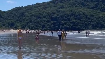 Praia Grande recebe centenas de turistas no começo desta semana Praias no litoral paulista já estão movimentadas | vídeo Banhistas caminhando na areia da praia - Reprodução Facebook