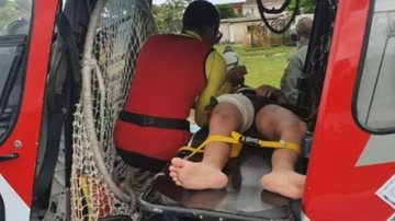 Bombeiros realizaram os primeiros socorros, mas foi necessário acionar o Águia para levar o adolescente ao hospital com urgência Rapaz sofre corte profundo enquanto surfava Adolesceste sendo colocando dento do helicóptero - Reprodução