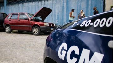 Veículo foi encontrado pelos agentes com as portas e janelas abertas Carro roubado em São Vicente Uno vermelho com capo aberto ao lado dos guardas e um casal - Divulgação/Prefeitura de São Vicente