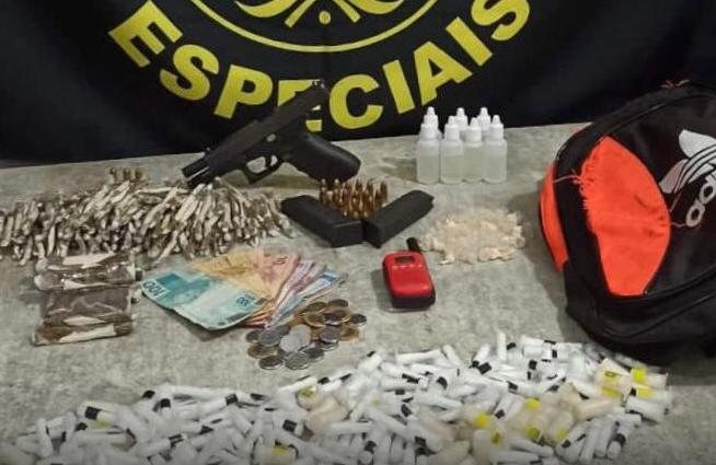 Todo o material foi apreendido e exames periciais solicitados Mochila de drogas e arma de fogo apreendida no Guarujá Mochila, drogas e arma em cima de uma mesa branca - Divulgação/Polícia Militar