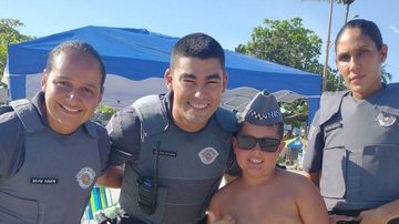 Foto foi tirada nesta segunda (27) em Ubatuba Crianças param policias para tirar fotos Criança posando com três policias militares - Reprodução Facebook