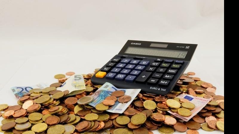 Estelionatários deixaram um prejuízo de quase R$ 21 mil Prejuízo financeiro Calculadora ao centro com moedas em volta - Divulgação