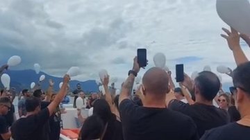 Amigos e pessoas próximas ao pescador soltaram balões branco e aplaudiram Luís Emoção: amigos homenageiam pescador encontrado morto Pessoa com bexigas brancas nas mãos - Reprodução
