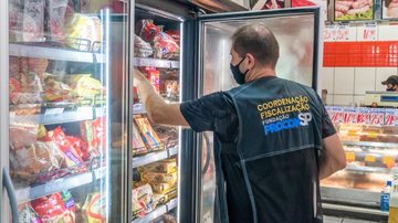 A ação aconteceu em parceria com o Órgão Municipal de Defesa do Consumidor Procon-SP Bertioga Agente do Procon-SP olhando os produtos dentro da geladeira do estabelecimento - Divulgação/Prefeitura de Bertioga