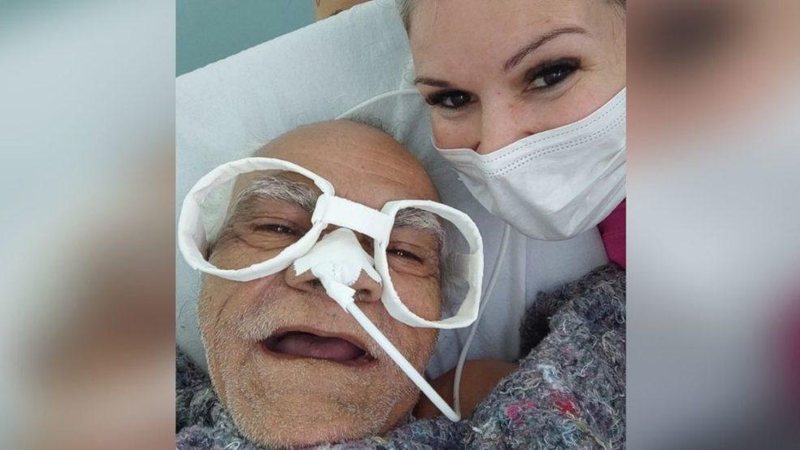 Idoso levou na brincadeira e adorou o novo óculos confeccionado pela enfermeira Enfermeira e paciente Enfermeira com máscara de proteção ao lado do idoso com os óculos de papel - Reprodução