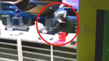 Além do infrator que foi flagrado pelas câmeras de segurança, um comparsa estaria ajudando e aguardando para fugir com os itens furtado Indivíduos quebram vitrine de ótima e furtam dezenas de produtos, em Santos | VÍDEO Individuo pegando objetos no balcão  - Reprodução