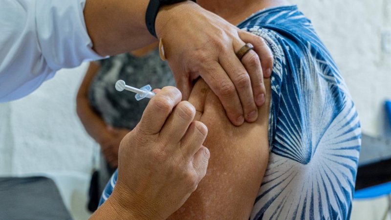 Corujão da Vacinação vacina contra a gripe, sarampo e covid-19 Corujão da Vacinação acontece em Bertioga a partir desta terça-feira (21) Pessoa recebendo vacina no braço - Prefeitura de Bertioga
