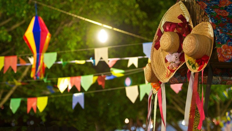 Evento será marcado por danças juninas tradicionais e venda de comidas típicas Festa Junina Bandeiras coloridas de festa junina e ao lado chapéus caipiras - Reprodução/Solutudo
