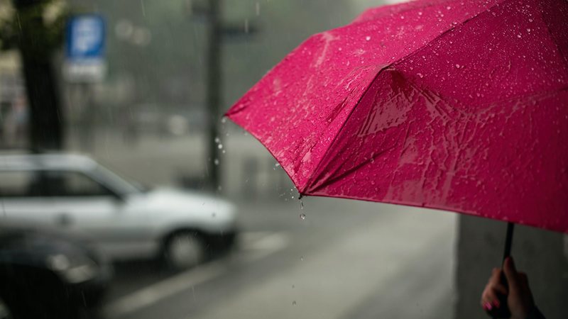 Inverno começa na próxima terça-feira (21), às 6:14 da manhã Último fim de semana de outono promete ser molhado no litoral de SP Pessoa com guarda-cguva vermelho aberto em rua - Erik Witsoe/Unsplash