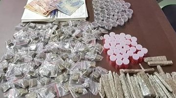 Drogas e dinheiro foram levados para a delegacia do município Drogas apreendidas Dinheiro e drogas em cima de uma mesa marrom - Divulgação
