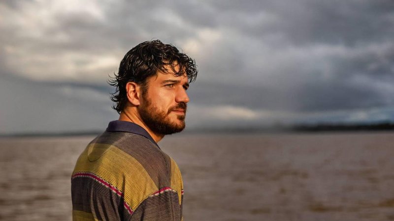 Marco Pigossi em foto promocional para a segunda temporada de Cidade Invisível Marco Pigossi Marco Pigossi homem branco de barba em foto de perfil - Divulgação