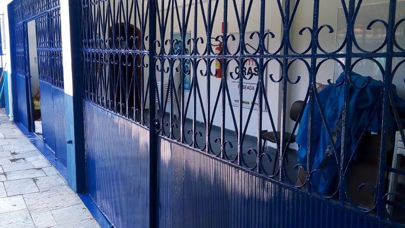 Um dos portões do local - agora pintado e reformado - em Guarujá Portão reformado Portão do Cras todo azul - Divulgação