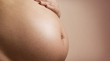 Mulher de 24 anos estava grávida de gêmeos; um deles foi encontrado no lixo Barriga de mulher grávida Mulher com a mão na barriga de grávida - Imagem ilustrativa