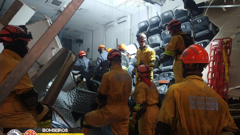 Galpão pertence a uma empresa de contêineres e 100 funcionários estariam no local na hora em que a estrutura veio abaixo Desabamento na Grande SP mata 6 e deixa 31 pessoas feridas nesta terça (20) Bombeiros trabalham dentro de galpão onde arquibancada desa - Twitter @BombeirosPMESP