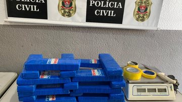 Ao todo, dentro de uma caixa de papelão, policiais encontraram 26 tijolos de maconha (cerca de 21.055 gramas) Maconha em tijolos Maconha em tijolos, fita e tesoura em cima de uma mesa da delegacia - Divulgação