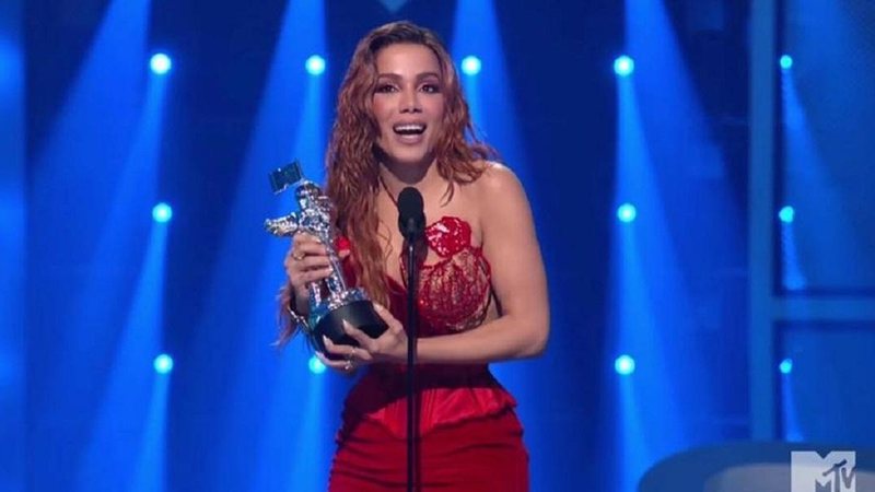 Anitta é a primeira artista solo brasileira a vencer uma categoria do VMAs Anitta Mulher de vestido vermelho com um prêmio nas mãos - Reprodução