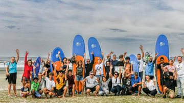 Alunos e professores de surf em modalidade gratuita oferecida pela prefeitura Grupo de surf Pessoas com as mãos para cima e prancha de surf atrás - Reprodução/Instagram