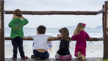 Imagem ilustrativa de crianças olhando para o mar de costas para a câmera Crianças Quatro crianças de costas - Pixabay