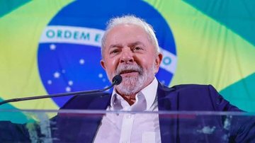 Lula usou sua rede social para parabenizar os jogadores pela vitória na Copa do Mundo Lula Lula falando em um microfone com a bandeira do Brasil atrás em um retroprojetor - Imagem: Ricardo Stuckert