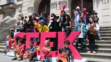 Evento geek de Santos concorre ao “Oscar dos Quadrinhos Nacional” Cosplays na escadaria da Prefeitura de Santos, ao lado de um letreiro da palavra "geek", em pink - Prefeitura de Santos