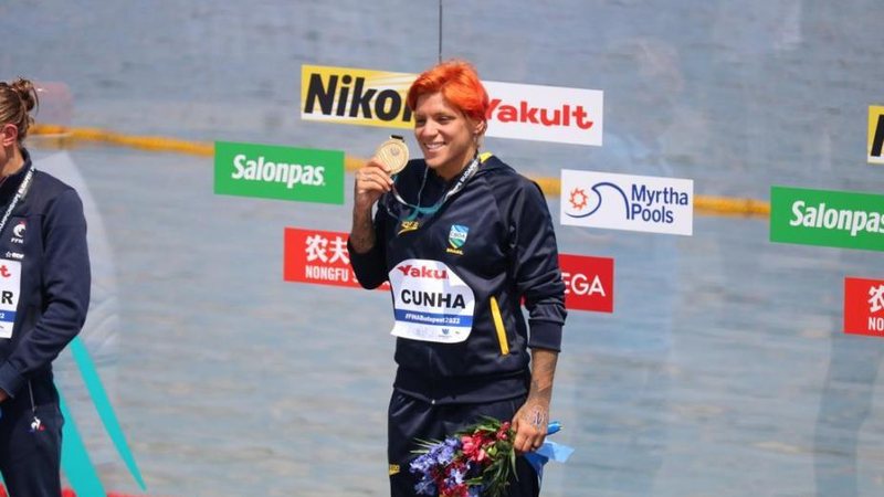 Ana Marcela compete na prova dos 10 km nesta quarta-feira (29) Nadadora Ana Marcela Cunha é bicampeã mundial de maratona aquática 5 km Nadadora Ana Marcela Cunha, no pódio, segurando a medalha de ouro - CBDA
